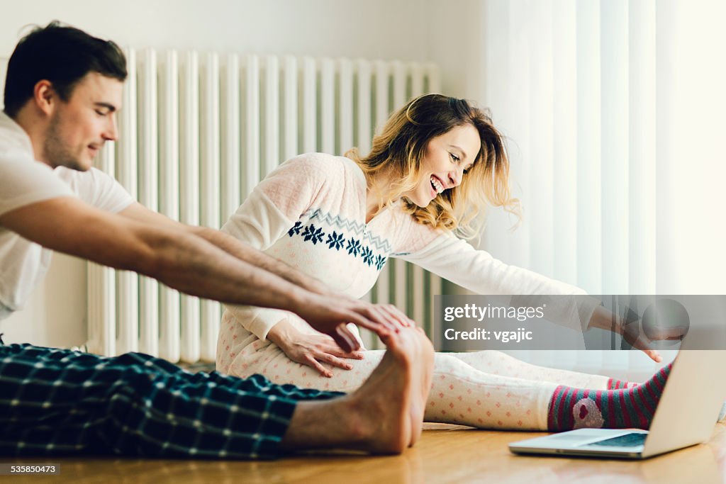 Couple Exercise in a living room with laptop.