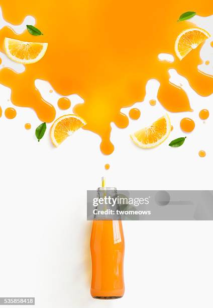 orange juice and slice splashing out from glass bottle. flat lay image - spray bottle stock-fotos und bilder