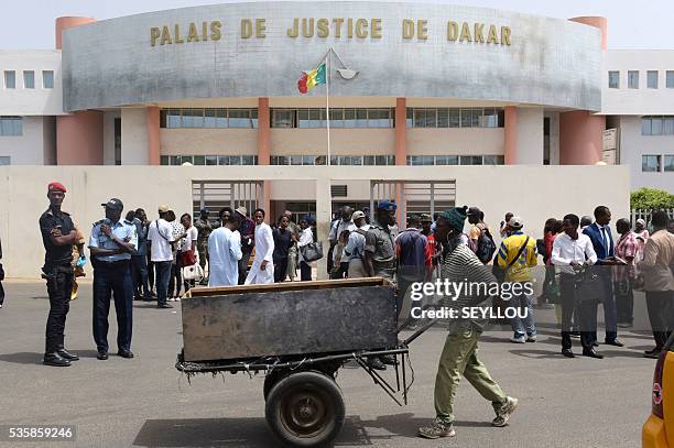 Man pushes a carriage past people and Senegalese security forces members standing outside Dakar Courthouse ahead of the sentencing of former Chadian...