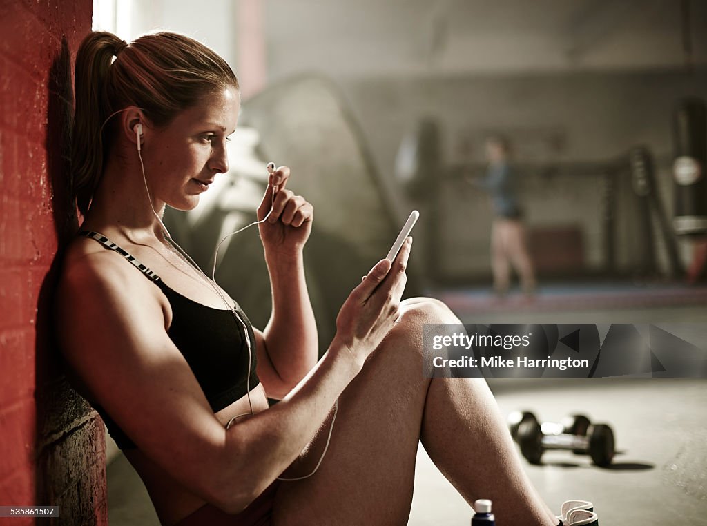 Woman resting in gym using mobile phone.