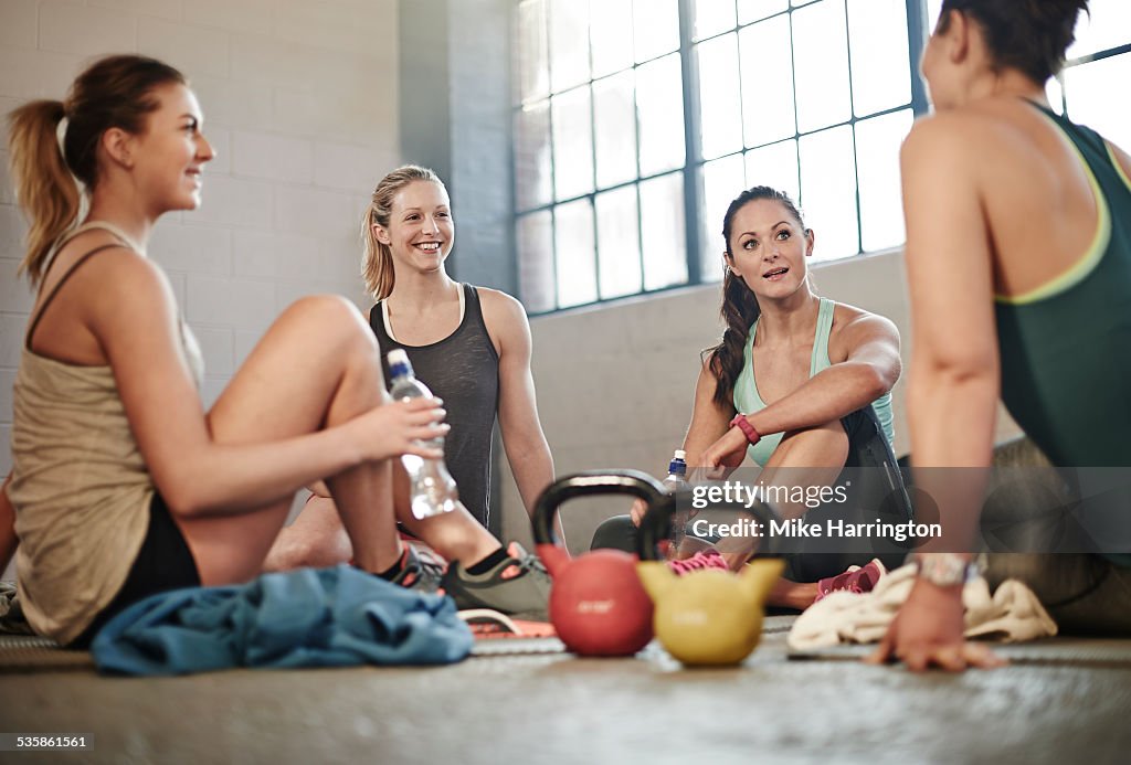Four healthy women in gym, taking a break