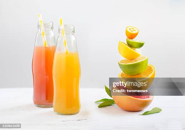 bottled citrus fruit juice with drinking straw along side with cut citrus fruits family stacked on white background. - acid stock pictures, royalty-free photos & images