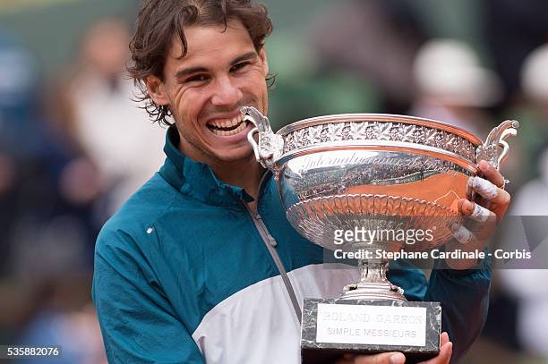 Rafael Nadal of Spain bites the Coupe des Mousquetaires trophy as he celebrates victory in the men's singles final against David Ferrer of Spain...