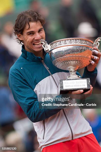 Rafael Nadal of Spain bites the Coupe des Mousquetaires trophy as he celebrates victory in the men's singles final against David Ferrer of Spain...