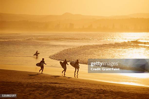 surfer on beach. - brisbane beach stock pictures, royalty-free photos & images