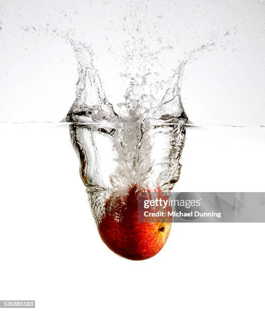 red apple splash - apple water splashing stock-fotos und bilder