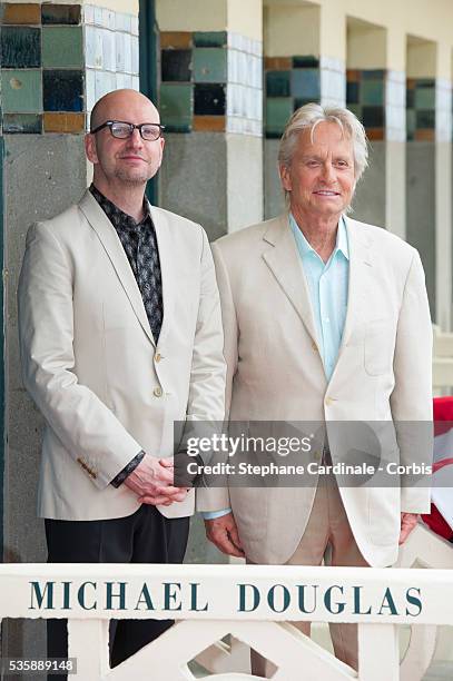 Michael Douglas and Steven Soderbergh pose next to the beach closet dedicated to them during a photocall on the Promenade des Planches for the movie...