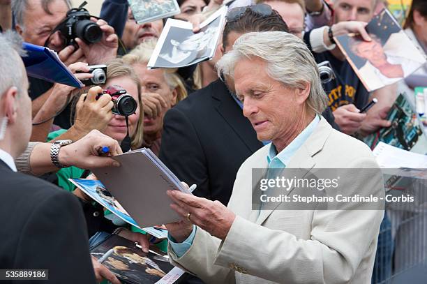 Actor Michael Douglas signs autographs as he unveils the beach locker room dedicated to him during a photocall on the Promenade des Planches for the...