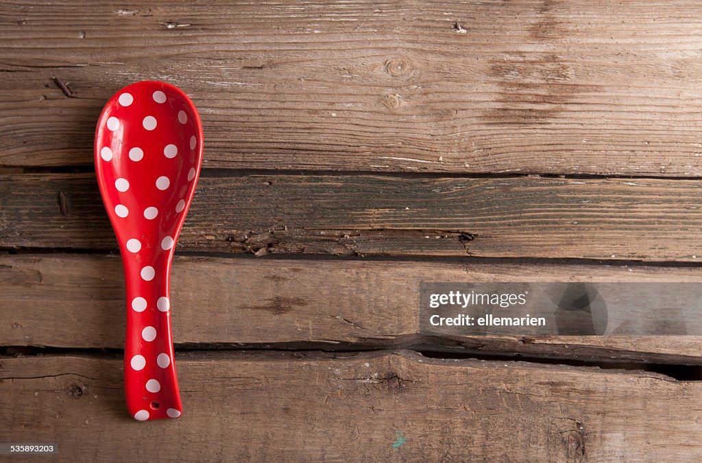 Cooking red spoon with polka dots on wooden background