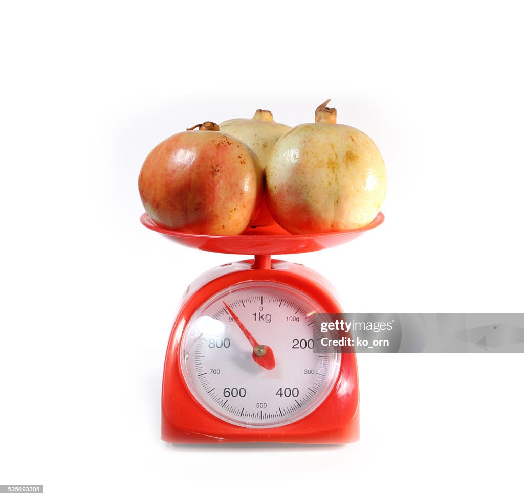 Pomegranate on red weighing scale