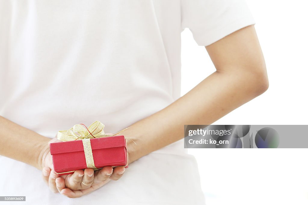 Woman hiding red gift box behind her back