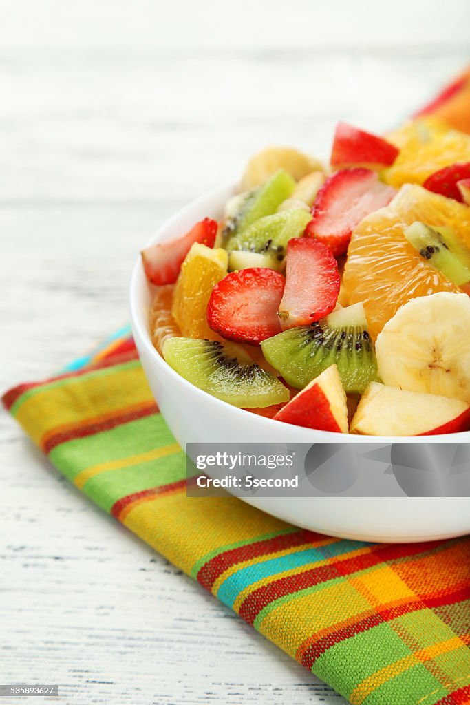 Fresh fruit salad on white wooden background