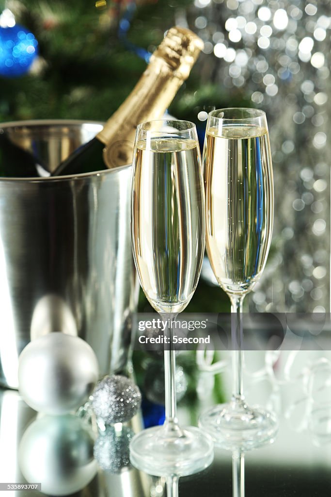 Glasses of champagne with bottle in a bucket on background