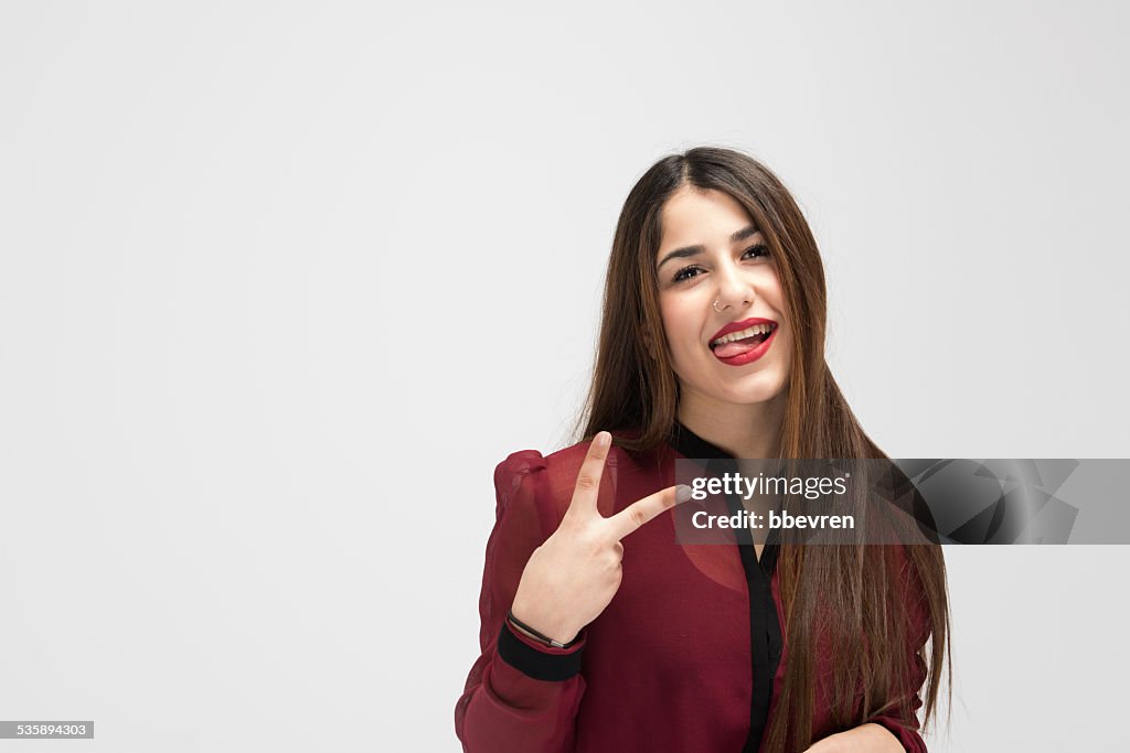 Cheerful attractive girl making victory sign while shpwing her t