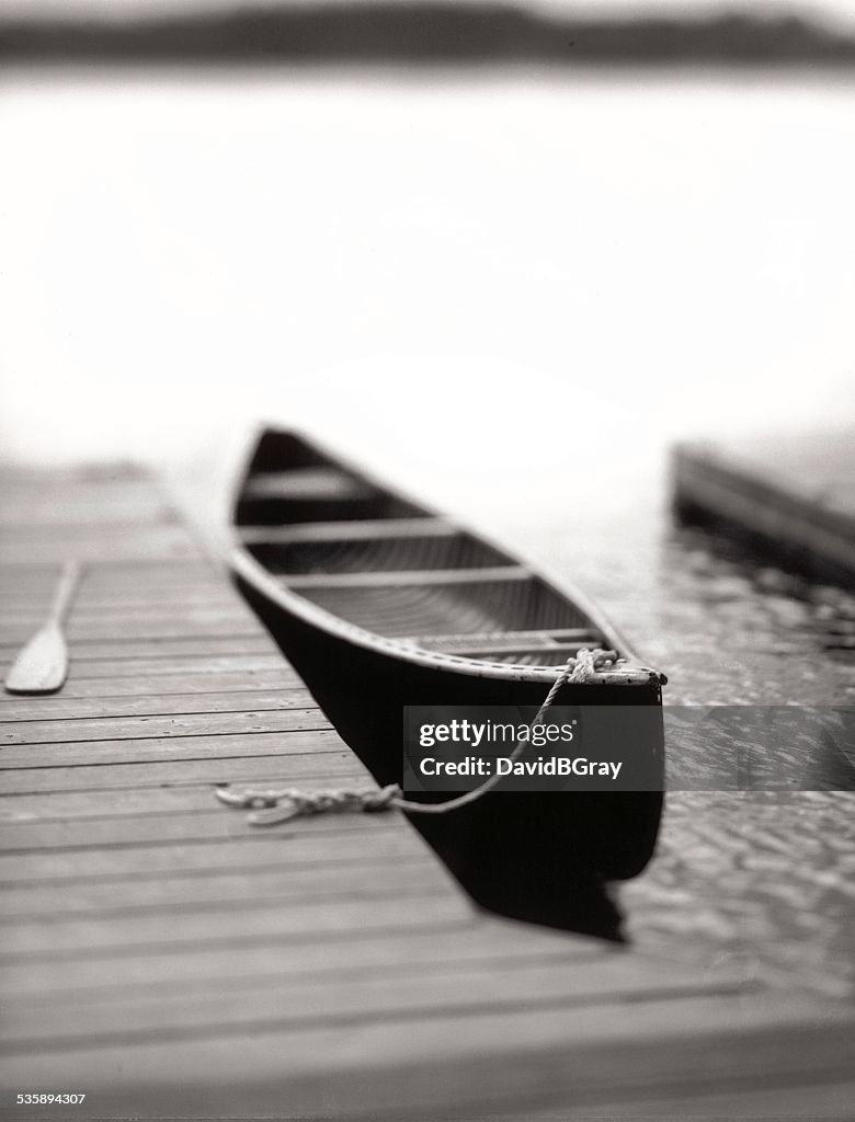 Solitude, tranquility : lone canoe tied to a dock on a lake