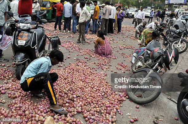People picking up onions that were thrown by farmers from Bijalpur and Rau as part of their protest in front of Collectorate on May 30, 2016 in...