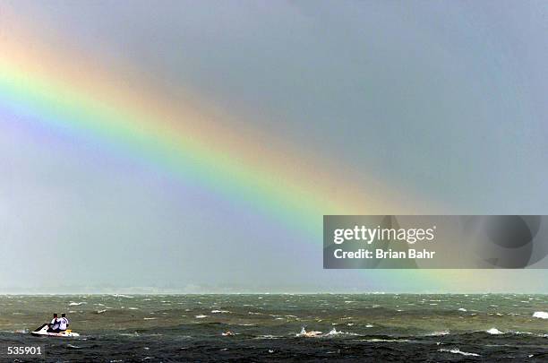 Women triathletes swim in choppy waters caused by Hurricane Michelle as a rainbow appears in the passing storm during the ITU Triathlon World Cup in...