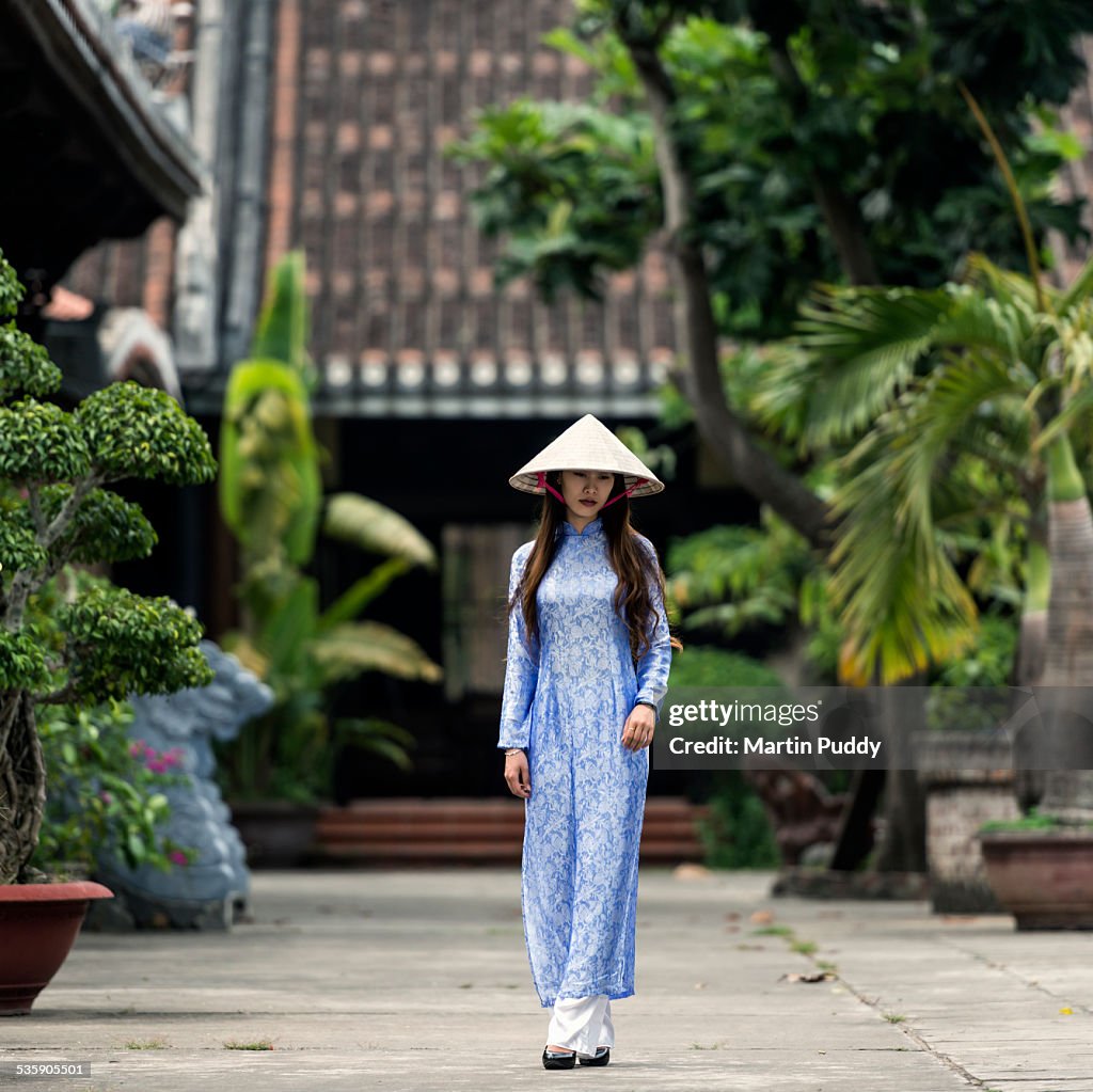 Vietnam, woman walking through temple courtyard