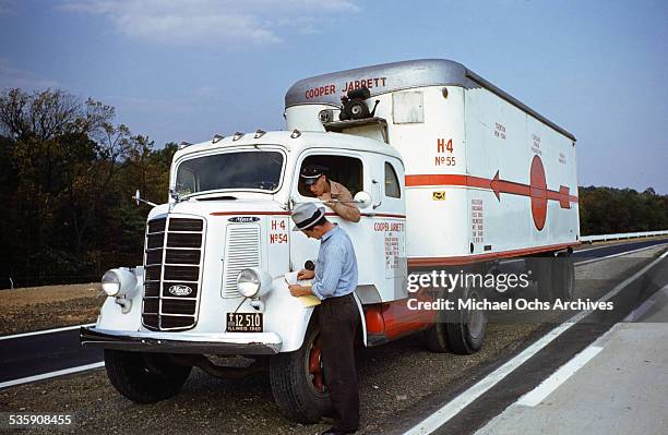 View of a truck driver, parking a Mack Truck alongside the interstate for Cooper Jarrett Motor Freight Lines in Illinois.