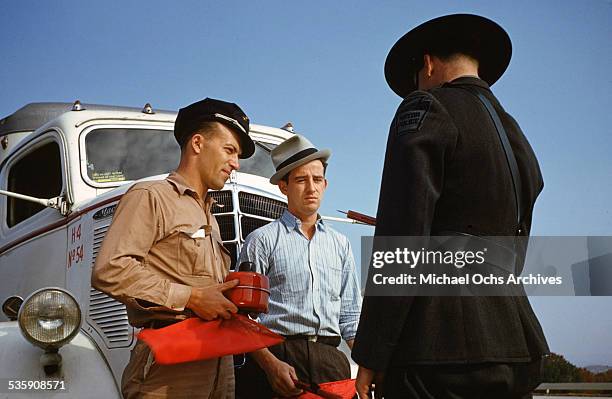 View of a truck driver, is stopped by a highway patrol officer as he drives a Mack Truck for Cooper Jarrett Motor Freight Lines in Illinois.