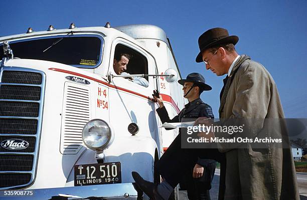 View of a truck driver, is stopped by a highway patrol officer as he drives a Mack Truck for Cooper Jarrett Motor Freight Lines in Illinois.