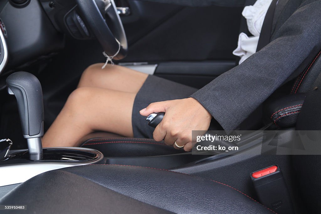 Woman pulling the hand brake in car