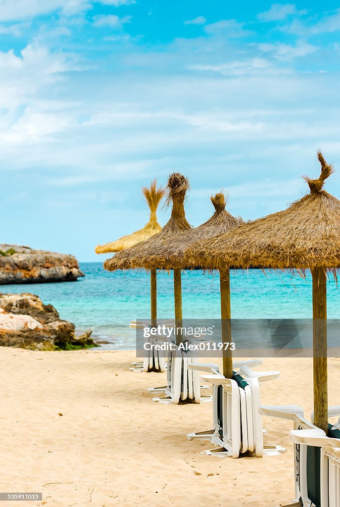 Straw parasols and beds on the sandy beach