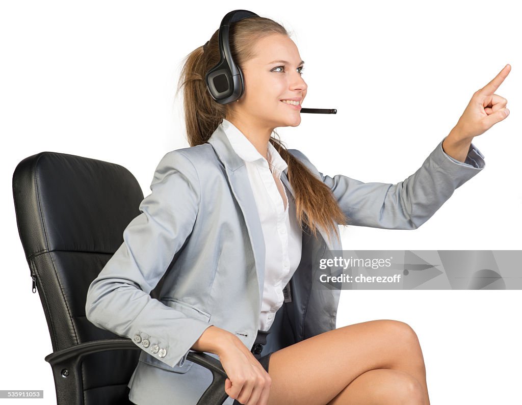 Businesswoman in headset sitting on office chair touching or pressing