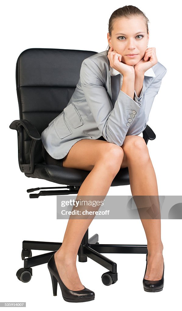 Businesswoman on office chair with head reclined upon her hands