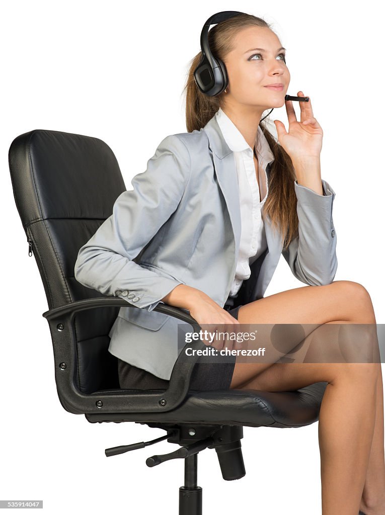 Businesswoman in headset sitting on office chair