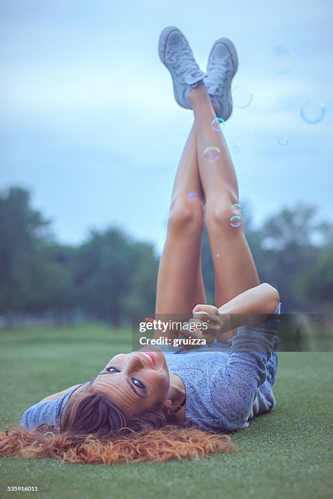 Young woman having fun and blowing bubbles outdoors