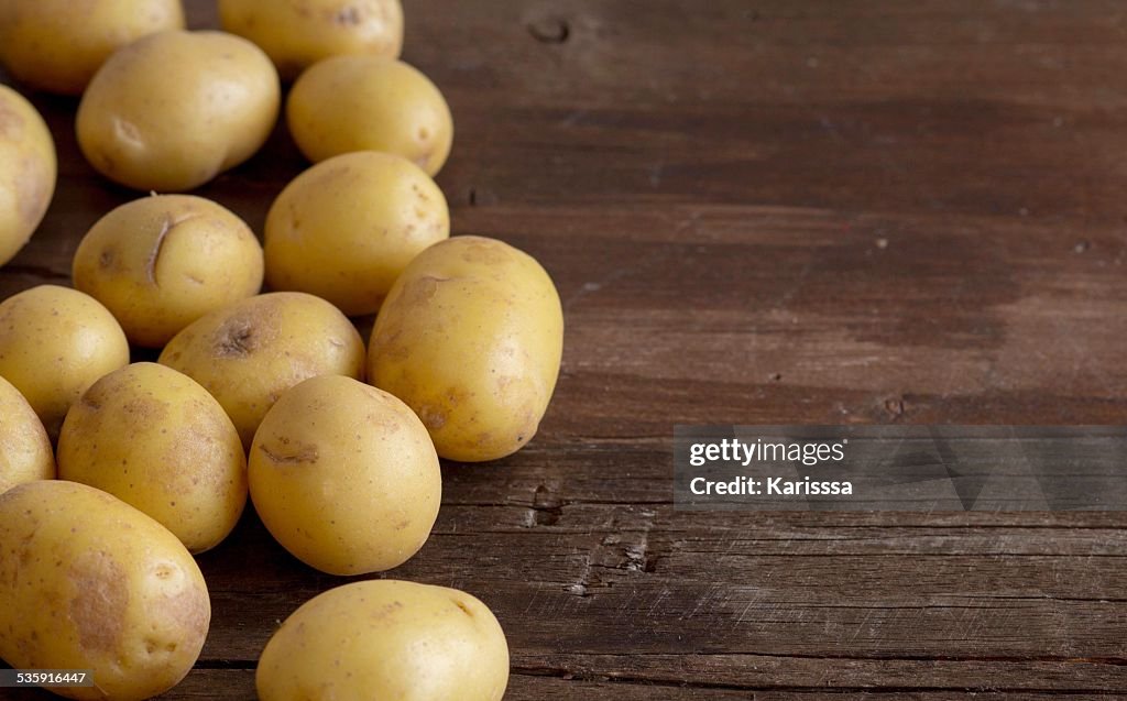 Young small potatos on wooden background