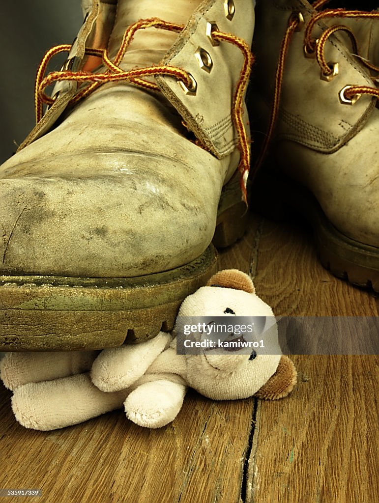 Teddy bear crushed by a heavy, old military boot.