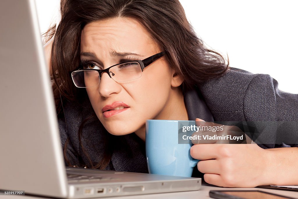 Sleepy and tired business woman on laptop, holding a coffee