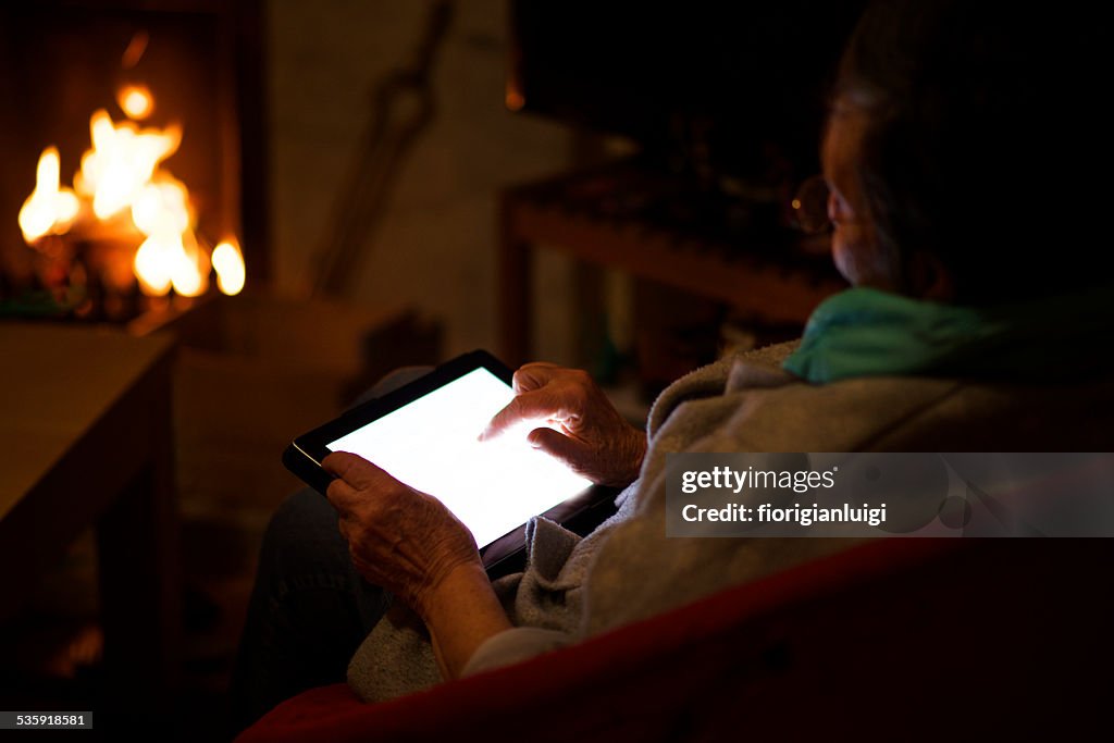 Großmutter vor dem Kamin mit seinem tablet