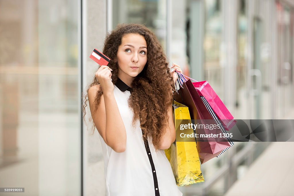 Pretty woman holding shopping bags and showing blank credit card
