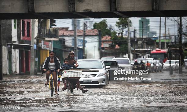 Cyclists and cars pass through a flooded street after heavy rains on May 30, 2016 in Recife, Brazil. Lack of proper drainage in areas is one of many...
