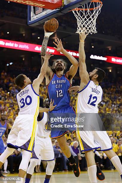 Steven Adams of the Oklahoma City Thunder goes up for a shot against Stephen Curry and Andrew Bogut of the Golden State Warriors in Game Seven of the...