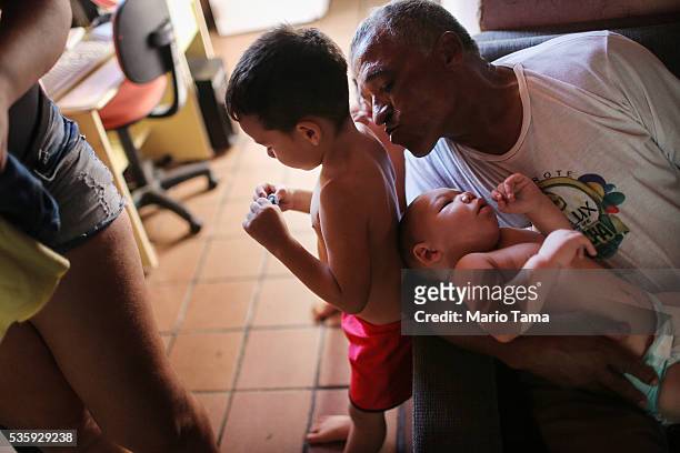 David Henrique Ferreira, 9-months-old, who was born with microcephaly, rests with his grandfather Julio as he leans to kiss David's brother Miguel on...