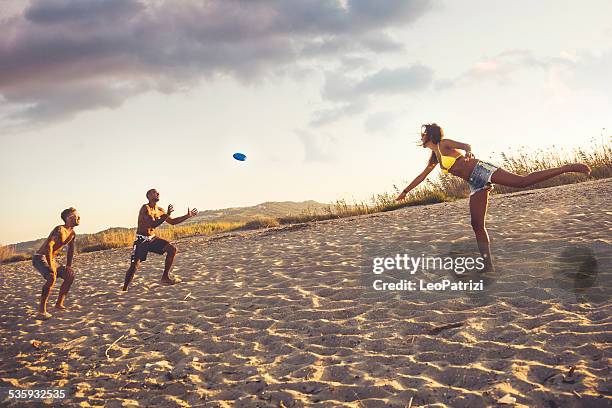 jugando en la playa con un freesbi - frisbee fotografías e imágenes de stock