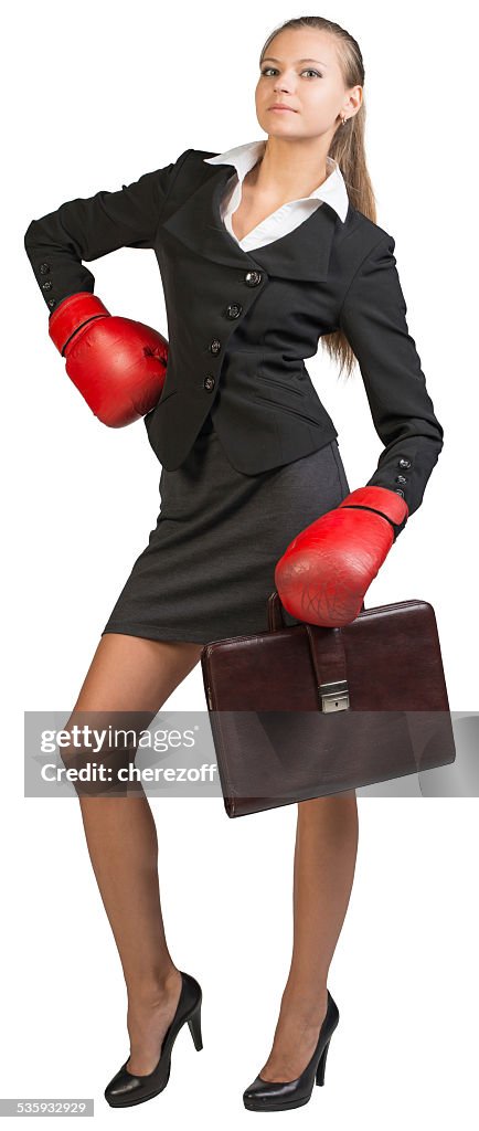 Donna d'affari con guantoni da boxe in piedi akimbo