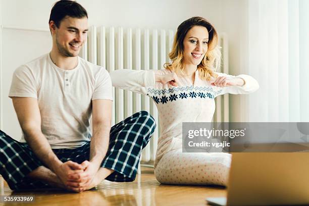 couple exercise in a living room with laptop. - babygro stock pictures, royalty-free photos & images