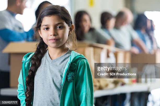 graves hispano hijo delante de las donaciones voluntarias clasificación de alimentos - giving a girl head fotografías e imágenes de stock