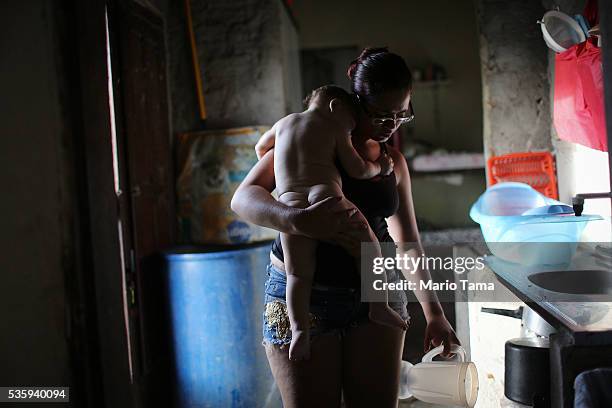 David Henrique Ferreira, nine-months-old, who was born with microcephaly, is carried by his mother Mylene after a bath on May 29, 2016 in Recife,...