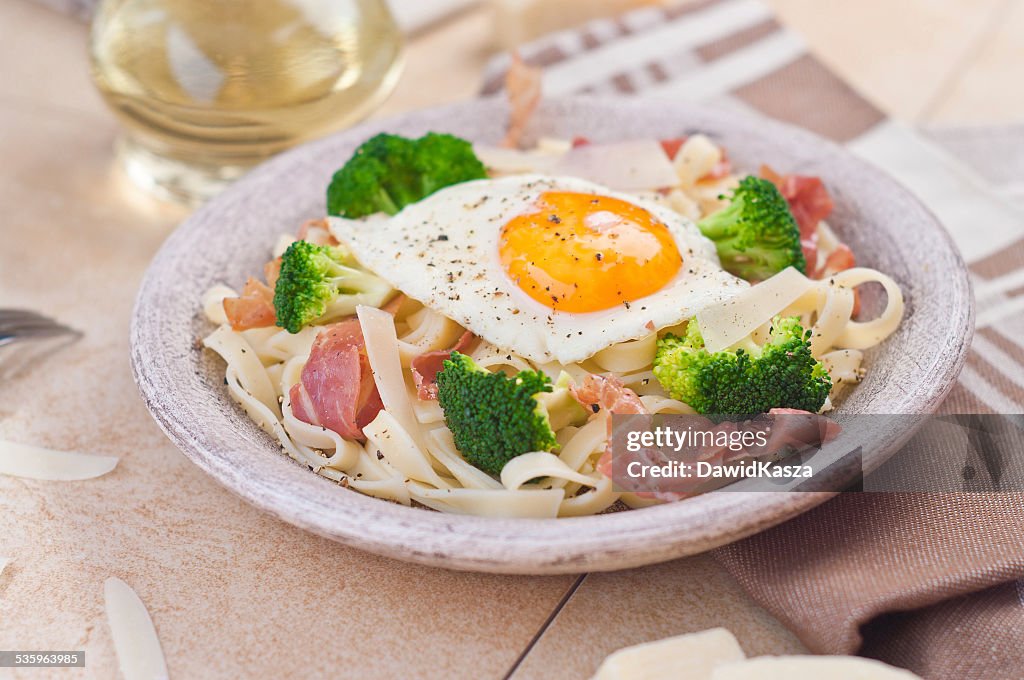 Tagliatelle pasta with broccoli, prosciutto and fried egg.