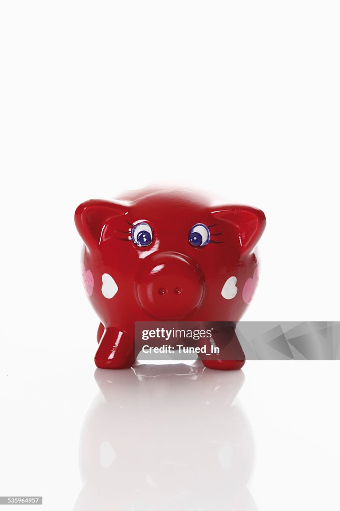 Piggy bank with heart shaped ornaments on white background