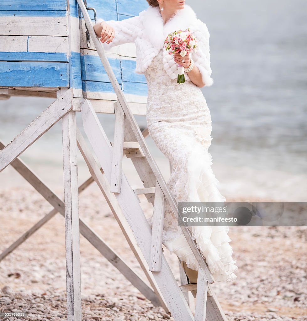 Sposa con bouquet di spiaggia in posa su una scala.