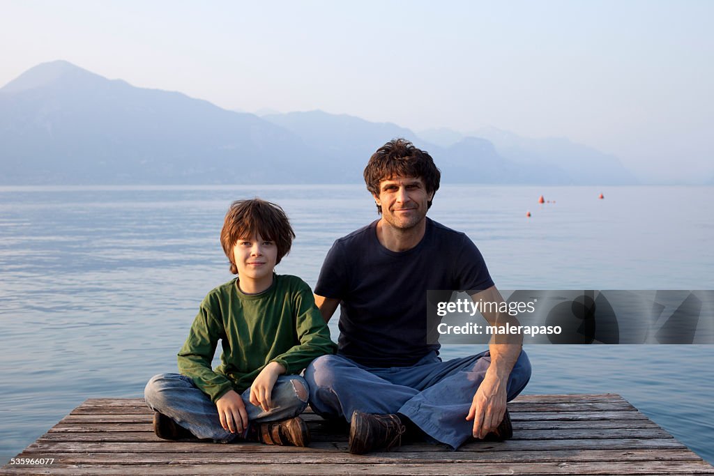 Father and son on a sitting on pier