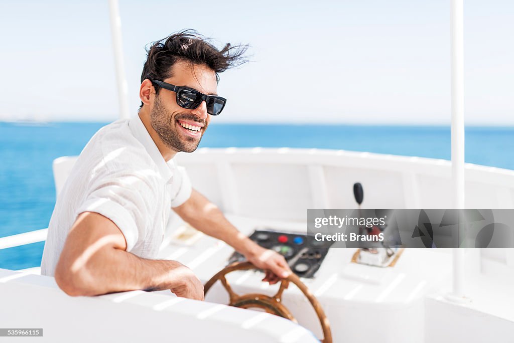 Young man driving a boat.