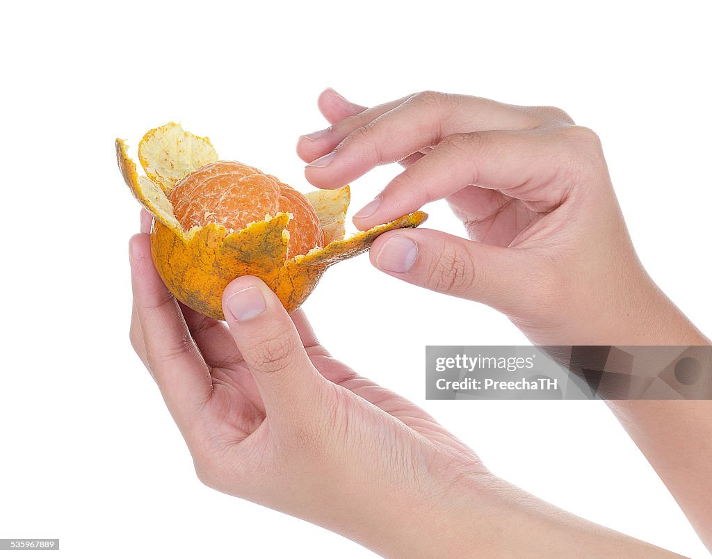 Hand holding and peeling orange isolated on white